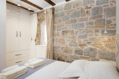 斯普利特斯普利特公寓酒店的一间卧室设有石墙和一张带毛巾的床。