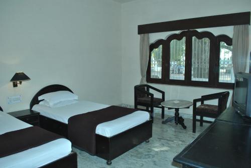 克久拉霍大理石宫酒店的一间卧室配有两张床和一张桌子及椅子