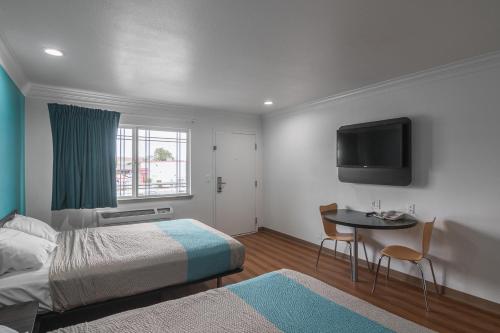 诺沃克罗德威市区酒店的一间卧室配有一张床、一张桌子和一台电视。