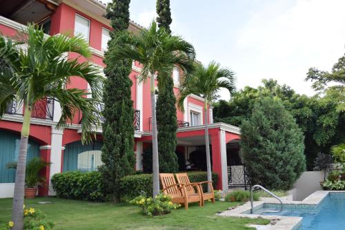 马那瓜Altos de Fontana的一座粉红色的房子,里面种有棕榈树,设有游泳池