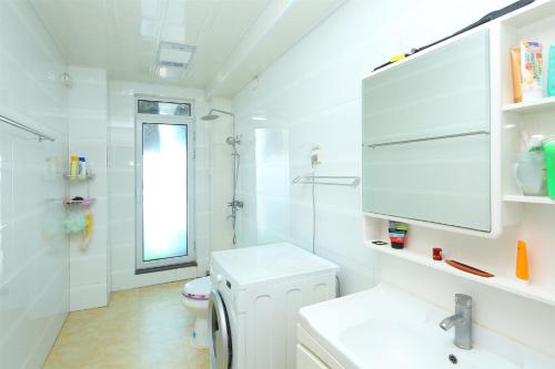 青岛青岛金沙滩全家幸福三居室海景公寓的白色的浴室设有卫生间和水槽。