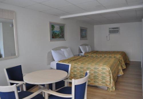 大洋城岛民汽车旅馆 的酒店客房带一张床、一张桌子和椅子