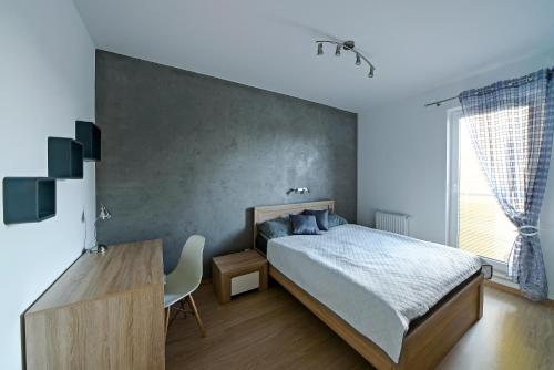 弗罗茨瓦夫Apartamenty City View od WroclawApartament-pl的一间卧室配有一张床、一张书桌和一个窗户。