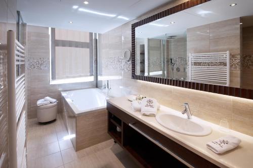 韦尔斯亚德里亚精品酒店的一间带水槽、浴缸和镜子的浴室
