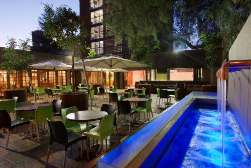 比勒陀利亚Hotel 224 & Apartments的一间带桌椅的餐厅和一个游泳池