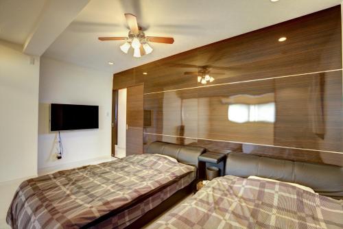 宜野湾市宜野湾露台度假公寓的一间卧室配有两张床和吊扇