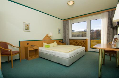 武茨巴赫雷恩施泰克公寓式酒店的一间卧室配有一张床、一张书桌和一个窗户。