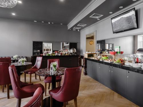 敖德萨优诺设计酒店的餐厅设有酒吧,配有红色椅子和桌子
