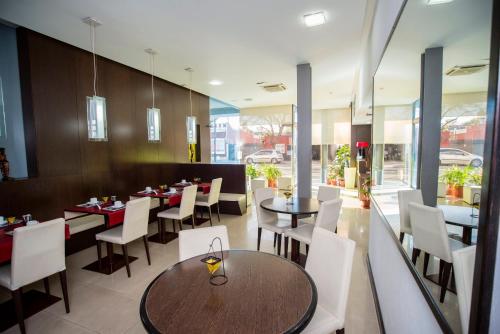 罗萨里奥Hotel Necof的用餐室配有桌子和白色椅子