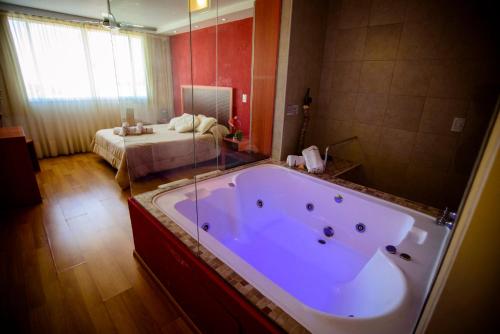 罗萨里奥Hotel Necof的配有床的房间的大浴缸