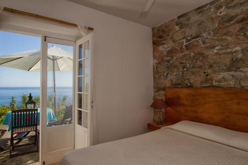 Ribeira QuenteCasa de Pedra的一间卧室配有一张床,庭院配有遮阳伞