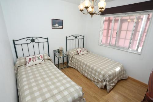 菲尼斯特雷Santa catalina 46的一间卧室设有两张床、一个窗户和一个吊灯。