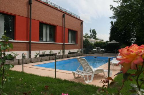 雷焦艾米利亚阿利罗尼酒店的一座带两把椅子的游泳池位于大楼旁