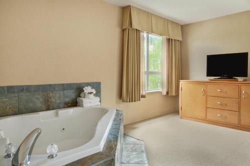 纳奈莫纳奈莫华美达酒店的带浴缸的大型浴室和电视。