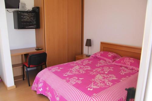 普拉亚Apartamento António的卧室配有粉红色的床和书桌