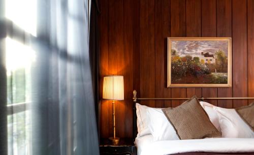 曼谷曼谷出版社酒店的一间卧室配有一张带灯具和绘画的床