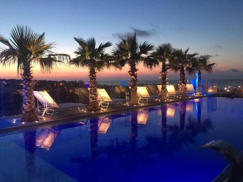 圣朱利安斯雨果精品酒店 - 仅限成人的游泳池在晚上设有椅子和棕榈树