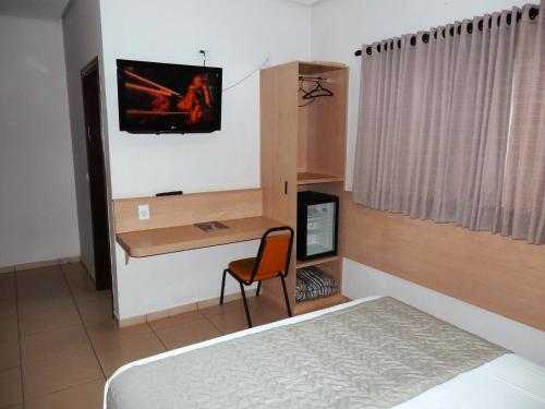 卡坦杜瓦Hotel Lider - Catanduva的一间卧室配有一张床和一张带电脑的书桌