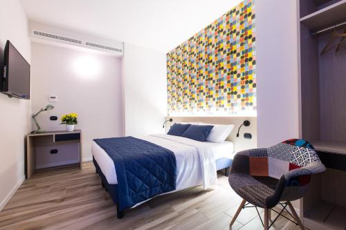 米兰伊索拉公寓式酒店的卧室配有一张床,墙上挂着色彩缤纷的绘画作品
