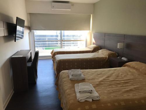圣贝尔纳多Hotel Luz y Fuerza San Bernardo - All Inclusive的酒店客房设有三张床和窗户。