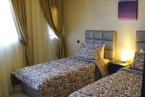 达赫拉Résidence Tamaya的酒店客房设有两张床和窗户。