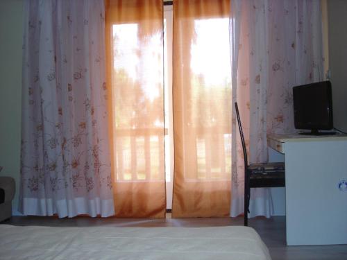 乌马格Apartman Darja的一间卧室设有两扇窗户,配有窗帘和电视