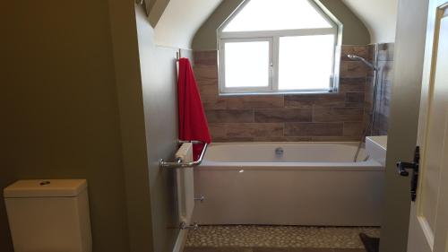 恩尼斯克朗Our Holiday Home的带浴缸、窗户和卫生间的浴室