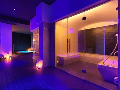 卡塞勒蒂索玛坎普DB维罗纳机场和国会酒店的浴室拥有紫色照明,设有淋浴和浴缸