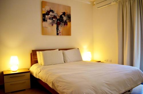 比尔泽布贾Hepburn Holiday Apartment的卧室配有带两盏灯的白色床
