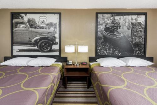 布卢明顿Super 8 by Wyndham Bloomington的酒店客房设有两张床,墙上挂有一辆汽车。