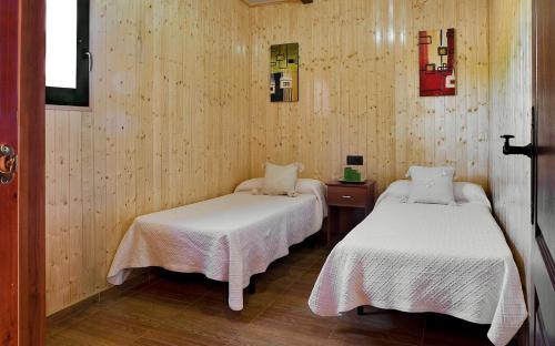 拉卡尔洛塔卡洛斯三世露营酒店的木墙客房的两张床