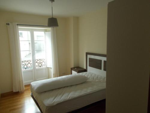 里瓦德奥Apartamento Ría de Ribadeo的卧室配有白色的床和窗户。