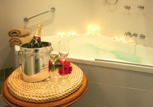 索伦托索伦托海滩汽车旅馆的浴室配有浴缸、一瓶香槟和玻璃杯