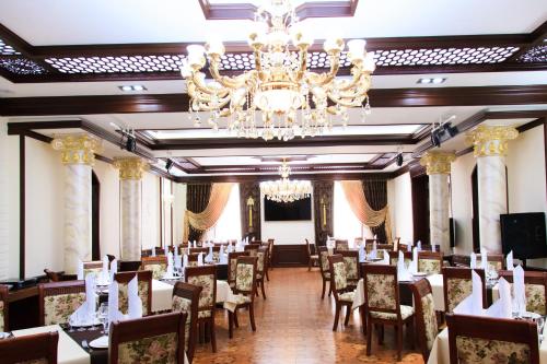 塔什干拉卡特广场酒店的一间带桌椅和吊灯的用餐室