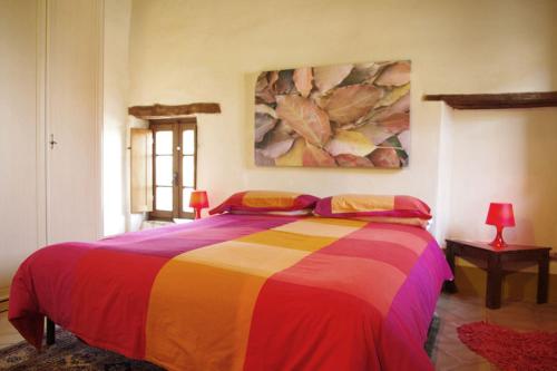 MontecastelliFarmhouse Tuscany的一间卧室配有一张色彩缤纷的床,墙上挂着一幅画作