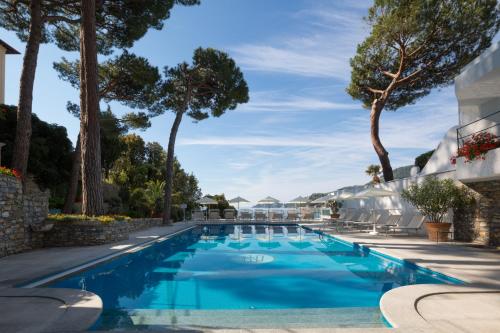 圣玛格丽塔-利古雷尹朋里阿雷皇宫酒店的拥有蓝色海水和树木的游泳池