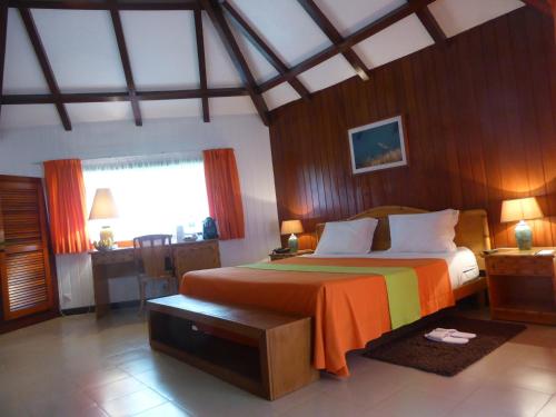 SantʼAnaClub Santana Beach & Resort的一间卧室配有一张带橙色毯子的大床