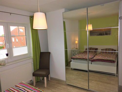 奈斯玛兹埃勒Ferienwohnung Krabbentaucher 2的一间卧室配有一张床、一把椅子和镜子