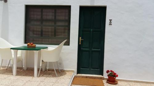 奥尔索拉Apartamentos Los Vientos (Apto 3)的一张桌子和椅子旁边的绿色门