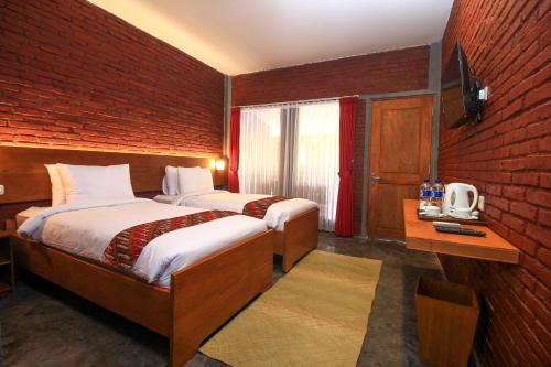 婆罗浮屠婆罗浮屠瓦伊德酒店的一间卧室设有两张床和砖墙