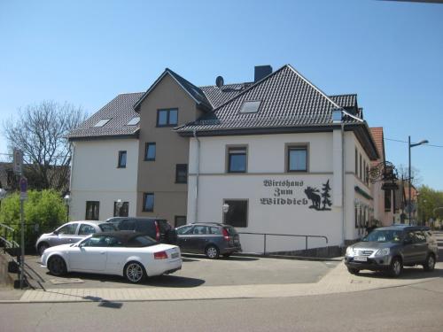 巴特拉珀瑙Wirtshaus zum Wilddieb的停车场内有车辆的建筑物