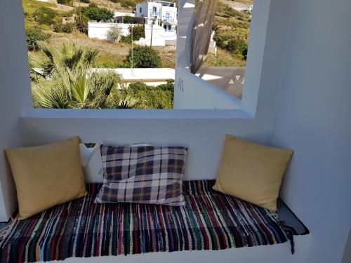 斯基罗斯岛Theo's Vacation Home的带两个枕头的长凳和窗户