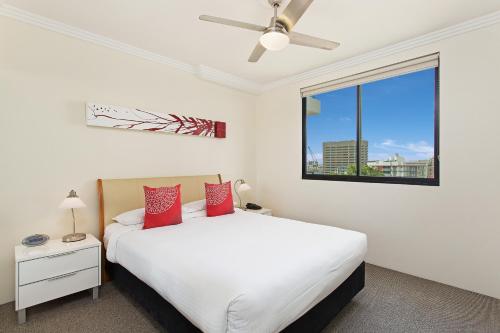 布里斯班Republic Apartments Brisbane City的卧室配有白色的床、红色枕头和窗户