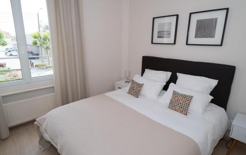 圣马洛Le Courtoisville Apartment的卧室配有带枕头的白色床和窗户。