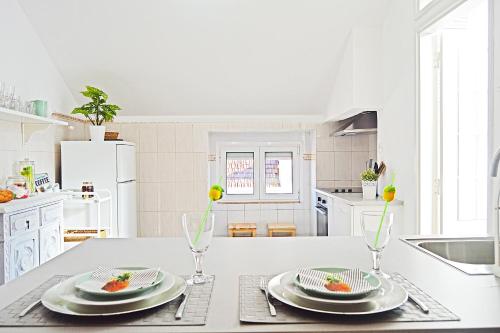 里斯本Belém Apartment的白色的厨房,配有带盘子和玻璃杯的桌子