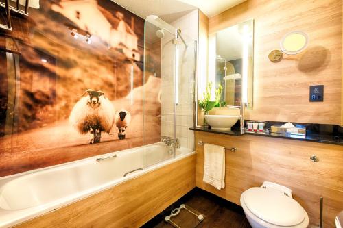 爱丁堡Leonardo Royal Edinburgh Haymarket的带浴缸的浴室,并展示了羊的照片