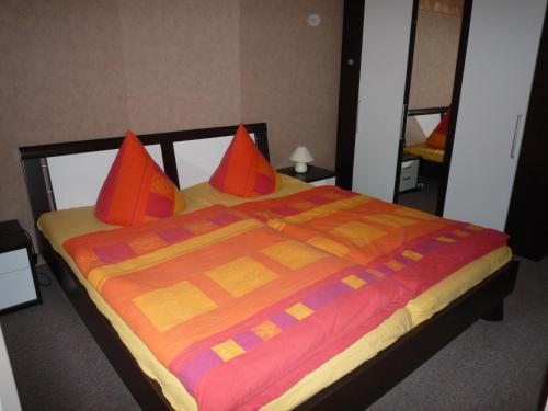 普鲁滕Zum alten Seemann的一张带橙色枕头和彩色毯子的床