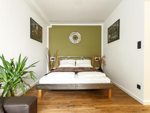 柏林迪尔花园公寓的卧室配有一张床,墙上挂着一个钟