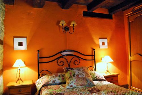 OlivánCasa Azon的一间卧室配有橙色墙壁、一张床和两盏灯
