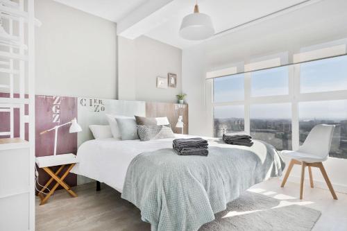 萨拉戈萨Mirador del Ebro的白色卧室配有一张大床和椅子